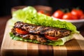 grilled seitan steak on bun, lettuce and tomatoes Royalty Free Stock Photo