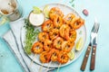 Grilled shrimp skewers or langoustines served with lime, garlic and sauce on a light blue concrete background. Seafood and beer. Royalty Free Stock Photo