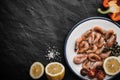 Grilled shrimps with lemon and vegetables on the ceramic plate on the black stone table Royalty Free Stock Photo