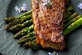 Grilled Sirloin beef steak on fried asparagus served on black slate plate with rosemary flowers Royalty Free Stock Photo