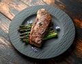 Grilled Sirloin beef steak on fried asparagus served on black slate plate with rosemary flowers Royalty Free Stock Photo