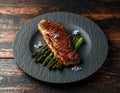 Grilled Sirloin beef steak on fried asparagus served on black slate plate with rosemary flowers Royalty Free Stock Photo