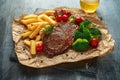 Grilled sirloin steak with potato fries, broccoli, beer and cherry tomatoes on crumpled paper Royalty Free Stock Photo