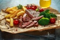 Grilled sirloin steak with potato fries, broccoli, beer and cherry tomatoes on crumpled paper Royalty Free Stock Photo