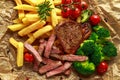 Grilled sirloin steak with potato fries, broccoli and cherry tomatoes on crumpled paper Royalty Free Stock Photo