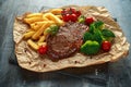 Grilled sirloin steak with potato fries, broccoli and cherry tomatoes on crumpled paper Royalty Free Stock Photo