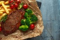 Grilled sirloin steak with potato fries, broccoli and cherry tomatoes on crumpled paper Royalty Free Stock Photo