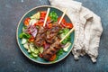 Grilled skewer meat beef kebabs on sticks served with fresh vegetables salad on plate on rustic concrete background from Royalty Free Stock Photo