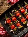 Grilled skewers of green asparagus, cherry tomatoes and sausage with the addition of herbs in a grill pan top view