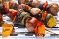 Grilled skewers of meat, sausages and various vegetables on a grill plate, outdoors, top view. Royalty Free Stock Photo