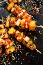 Grilled skewers with pineapple fruit and chicken meat sprinkled with sesame seeds, chilli pepper and fresh herbs