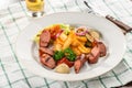 Grilled sliced sausage served with beer, french fries, zucchini and ketchup on the side for Octoberfest on the table