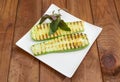 Grilled sliced vegetable marrow on square dish on rustic table Royalty Free Stock Photo