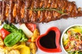 Grilled smoked pork ribs with french fries and soy sauce and salad on wooden board Royalty Free Stock Photo