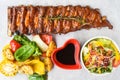 Grilled smoked pork ribs with french fries and soy sauce and salad on wooden board Royalty Free Stock Photo