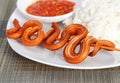 Grilled snake on skewer with chili sauce and rice on white plate on mat