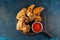 Grilled spicy chicken wings with ketchup on a black plate on a dark slate, stone or concrete background. Top view with Royalty Free Stock Photo