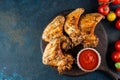 Grilled spicy chicken wings with ketchup on a black plate on a dark slate, stone or concrete background. Top view with Royalty Free Stock Photo