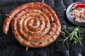 Grilled spiral sausages on a black background of charcoal.