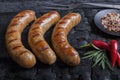 Grilled spiral sausages on a black background of charcoal.