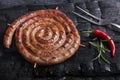 Grilled spiral sausages on a black background of charcoal