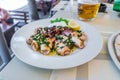 Grilled squids with herbs, garlic and lemon on white plate close-up. Popular and delicious Mediterranean meal