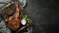 Grilled steak on the bone, herbs and spices on a wooden background. Barbecue. Top view. Royalty Free Stock Photo