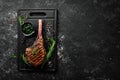 Grilled steak on the bone. Tomahawk steak on a black stone background. Top view. Free copy space Royalty Free Stock Photo