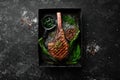 Grilled steak on the bone. Tomahawk steak on a black stone background. Top view. Free copy space Royalty Free Stock Photo