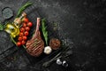 Grilled steak on the bone. Tomahawk steak on a black stone background. Top view. Free copy space Royalty Free Stock Photo