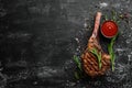 Grilled steak on the bone. Tomahawk steak on a black stone background. Top view. Free copy space Royalty Free Stock Photo