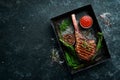 Grilled steak on the bone. Tomahawk steak on a black stone background. Top view. Free copy space Royalty Free Stock Photo