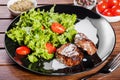 Grilled steak meat with fresh vegetable salad, tomatoes and sauce on black plate, Royalty Free Stock Photo