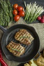 Grilled steak on a round grill pan, garnished with spices for meat, rosemary, greens and vegetables on a dark wooden background Royalty Free Stock Photo