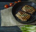 Grilled steak on a round grill pan, garnished with spices for meat, rosemary, greens and vegetables on a dark wooden background. Royalty Free Stock Photo