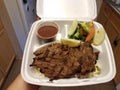 Grilled steak and salad and beans and rice in take out container