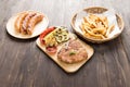 Grilled Steak with salad, french fries and sausage on wooden background Royalty Free Stock Photo