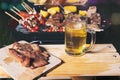 Grilled steak with tomatoes and corn on cutting board and mug of beer on wooden table