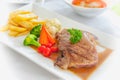 Grilled steaks, French fries and vegetables Royalty Free Stock Photo