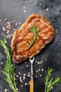 Grilled Striploin steak or strip new York on a meat fork. Black background. Top view