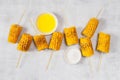 Grilled sweet corn on the sticks, grey textured table Royalty Free Stock Photo