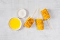 Grilled sweet corn on the sticks, grey textured table Royalty Free Stock Photo