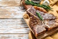 Grilled T bone steak on a chopping Board. Cooked tbone beef. White wooden background. Top view. Copy space