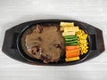 Grilled T-bone steak on hot plate, with vegetables. Royalty Free Stock Photo