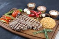 Grilled T-bone steak seasoned with spices and fresh herbs served on a wooden board with fresh tomato , fried vegetables, tomatoes, Royalty Free Stock Photo