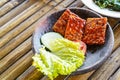 Grilled tempeh or fried tempeh with red barbecue sauce, vegetables and chili sauce served on an earthenware mortar