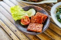 Grilled tempeh or fried tempeh with red barbecue sauce, vegetables and chili sauce served on an earthenware mortar