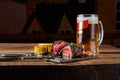 Grilled tenderloin Steak roastbeef and mushrooms sauce on black cutting board and glass of beer on wooden table Royalty Free Stock Photo