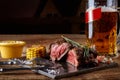 Grilled tenderloin Steak roastbeef and mushrooms sauce on black cutting board and glass of beer on wooden table Royalty Free Stock Photo