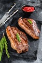 Grilled top sirloin cap or picanha steak on a stone chopping Board. Black background. Top view